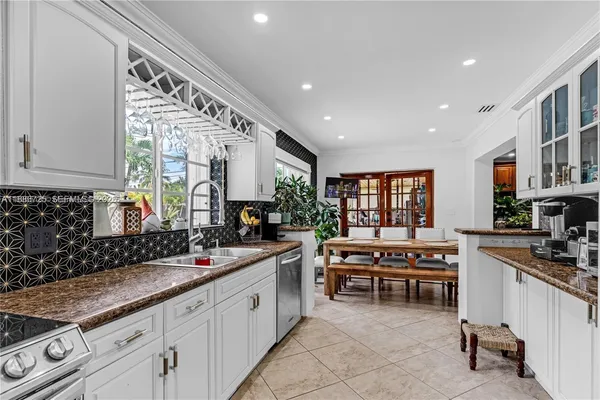 a large white kitchen with stainless steel appliances granite countertop a sink and cabinets