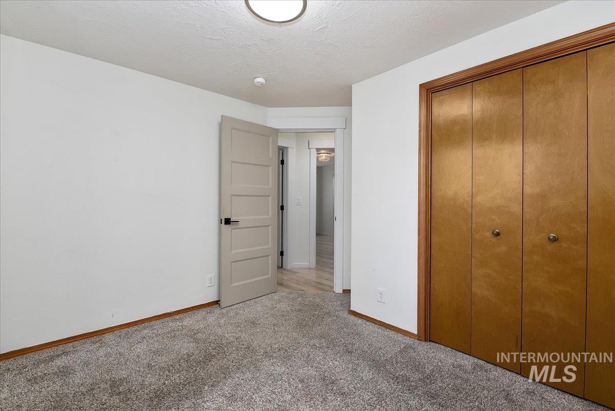 9215 West Preece Street Boise, ID 83704 - Photo 10 of 22 Carpeted room with a five-panel interior door, wood-finish bi-fold closet doors, white painted walls, and a flush-mount ceiling light fixture