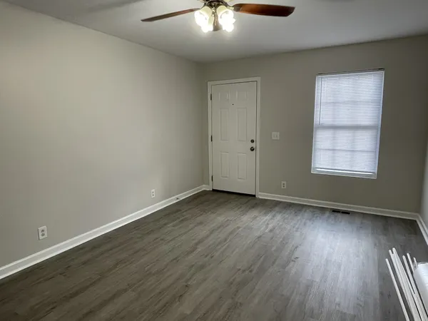 an empty room with wooden floor and windows