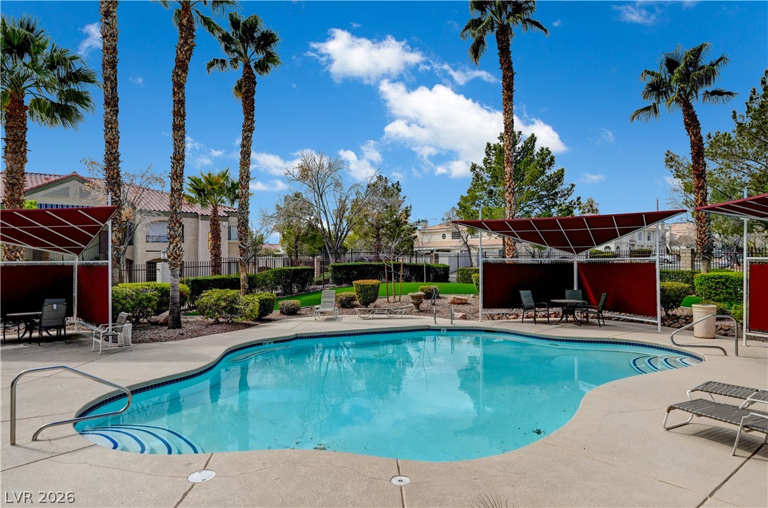 7885 West Flamingo Road, Unit 1050 Las Vegas, NV 89147 - Photo 54 of 62 Palm trees fringe a sparkling pool, inviting relaxation on a bright, sunny day.