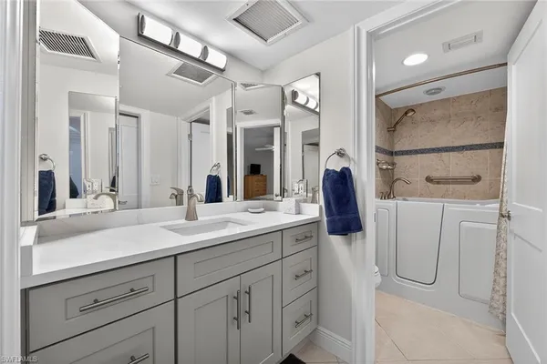 a bathroom with a double vanity sink mirror and bathtub