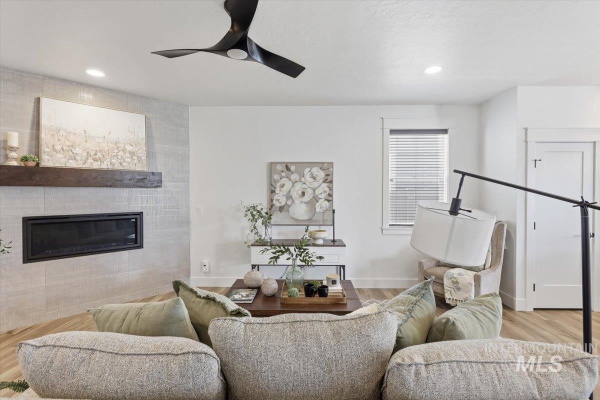 5897 West Riva Capri Street Meridian, ID 83646 - Photo 10 of 50 Living area featuring a modern linear fireplace with a substantial wood mantel, set against a light-toned tile surround