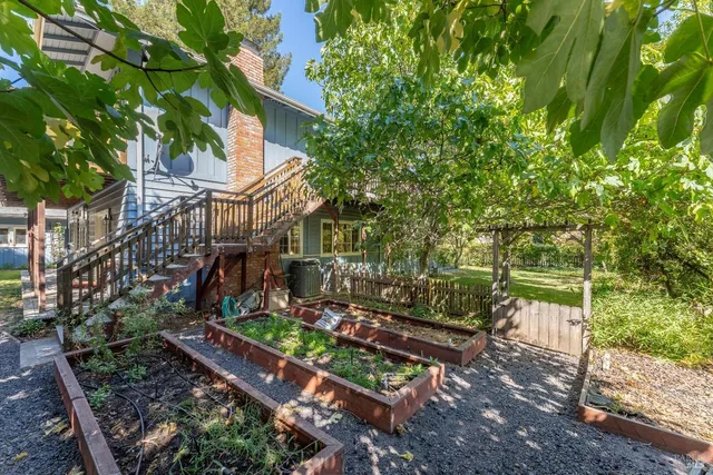 a backyard of a house with large trees and plants