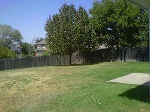 7929 Park Ridge Drive Fort Worth, TX 76137 - Photo 13 of 13 Spacious backyard featuring a large grass area, mature trees, a wood fence perimeter, and a concrete patio slab