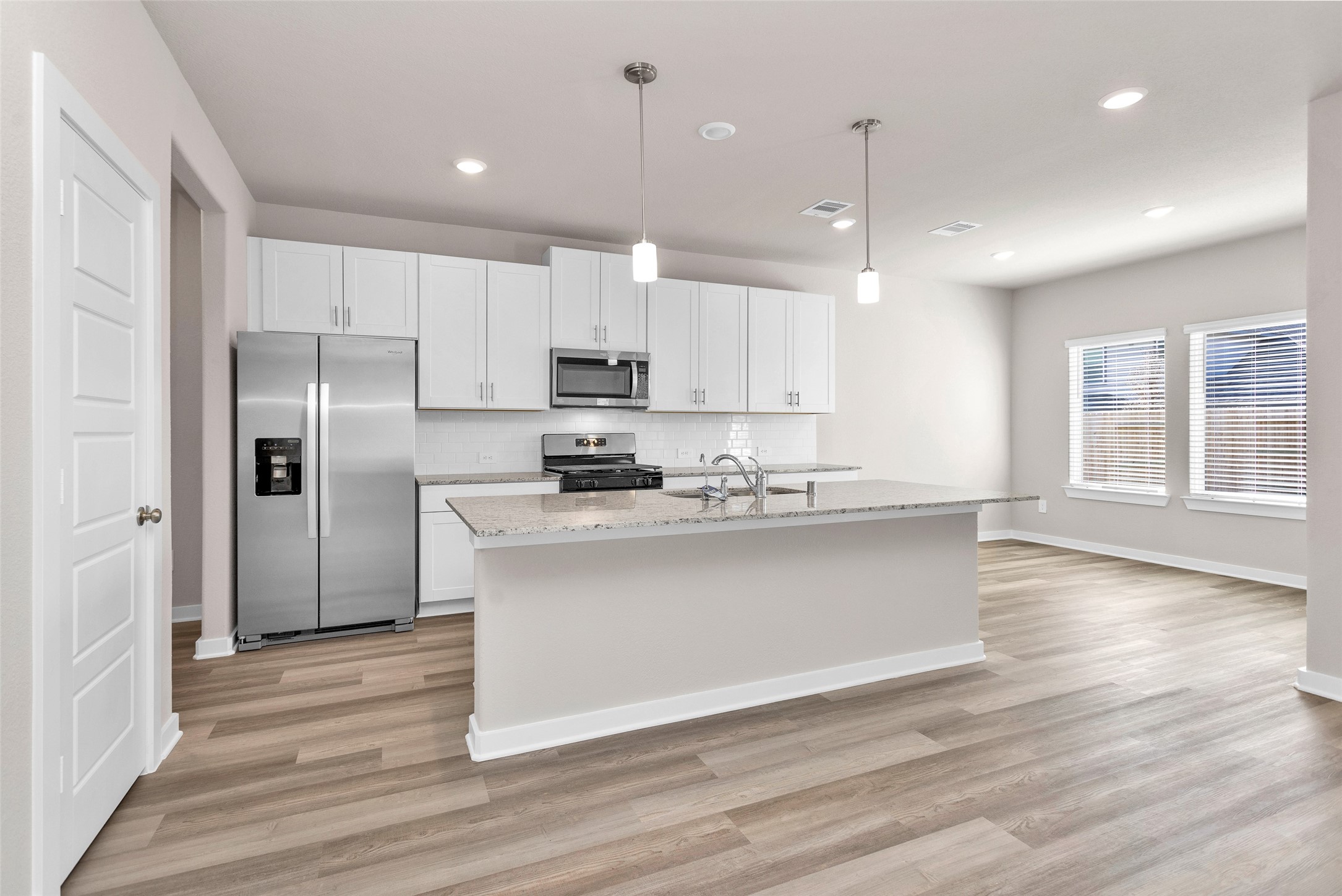 1406 Waggoner Rnch Trail Conroe, TX 77301 - Photo 14 of 43 a kitchen with stainless steel appliances kitchen island granite countertop a refrigerator a stove a sink and white cabinets with wooden floor