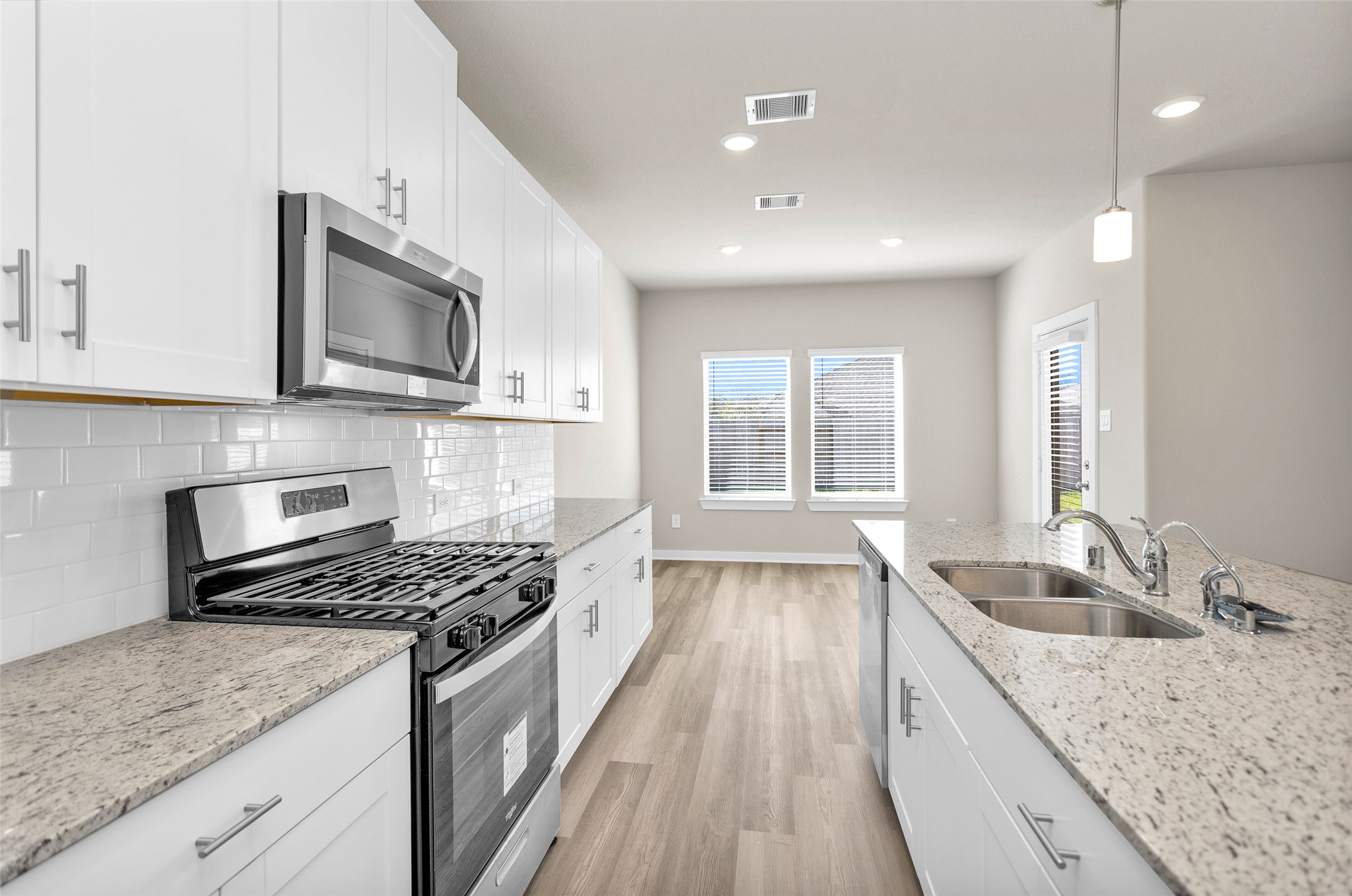 1406 Waggoner Rnch Trail Conroe, TX 77301 - Photo 17 of 43 a kitchen with granite countertop kitchen island wooden cabinets a stove a sink and a window