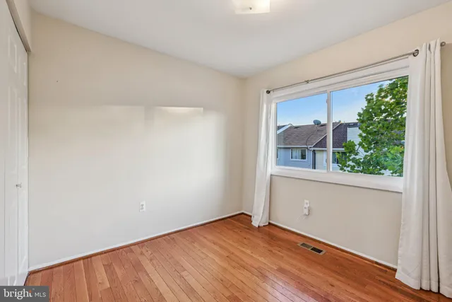 a view of an empty room with closet and a window