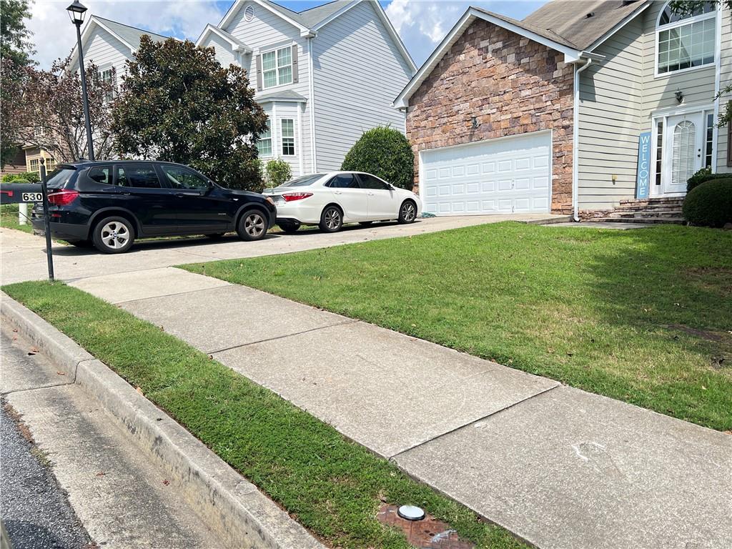 a view of a yard with a car parked in front of a house