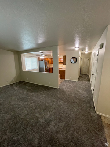 101 1501 Monroe, Unit 101 Ogden, UT 84404 - Photo 12 of 24 Empty room with a textured ceiling, dark carpet, and a ceiling fan