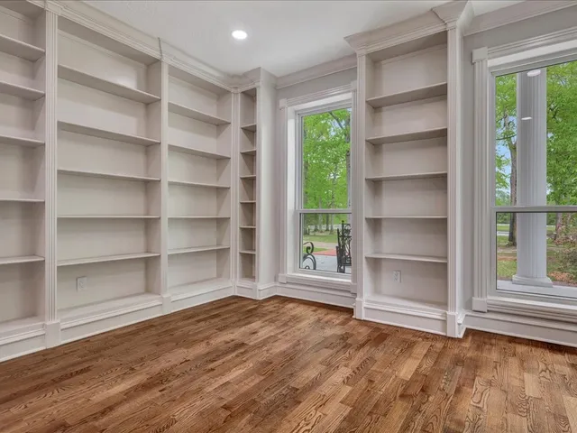 a view of an empty room with a window and wooden floor