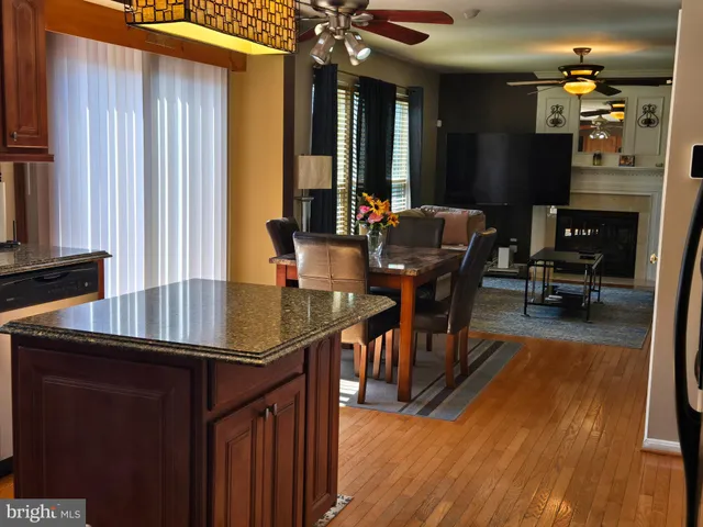 a living room with furniture a fireplace and a dining table with wooden floor