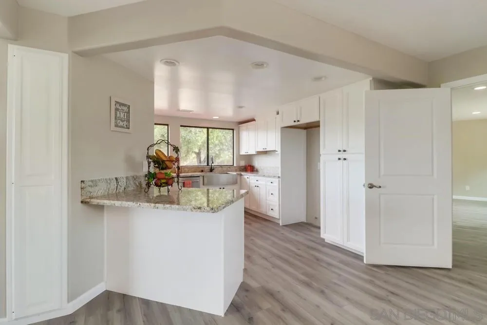 1660 Grove Road El Cajon, CA 92020 - Photo 10 of 44 a view of a kitchen with kitchen island a sink wooden floor and a large window