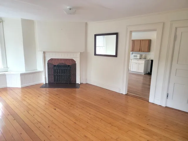 a view of empty room with wooden floor and fireplace
