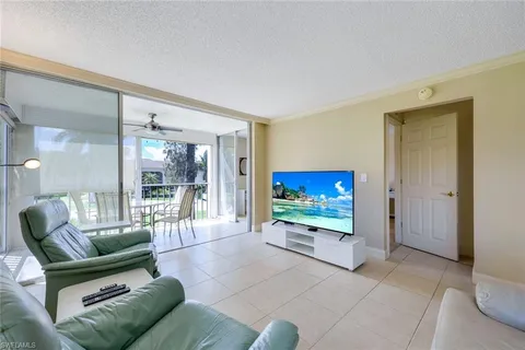 a living room with furniture a flat screen tv and a floor to ceiling window