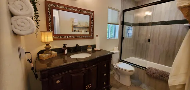 a bathroom with a granite countertop sink mirror vanity and toilet
