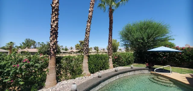 a view of a swimming pool with a table and chairs under an umbrella