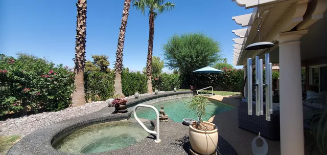 a backyard of a house with a table and chairs potted plants