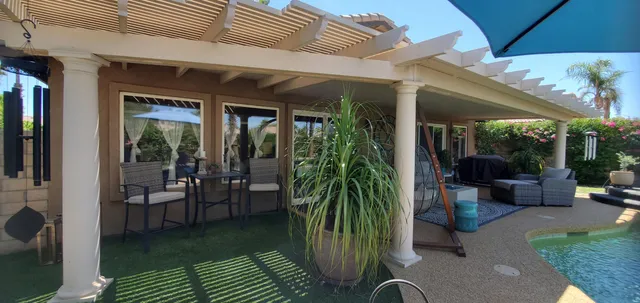 a view of a patio with table and chairs potted plants and floor to ceiling window