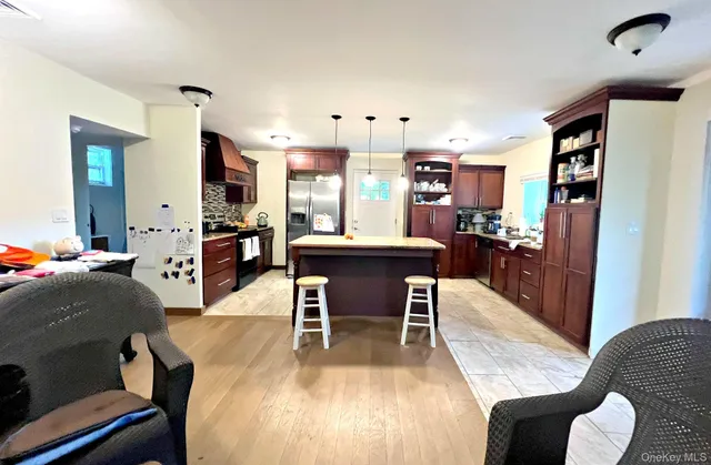 a kitchen with stainless steel appliances granite countertop a sink a refrigerator and chairs