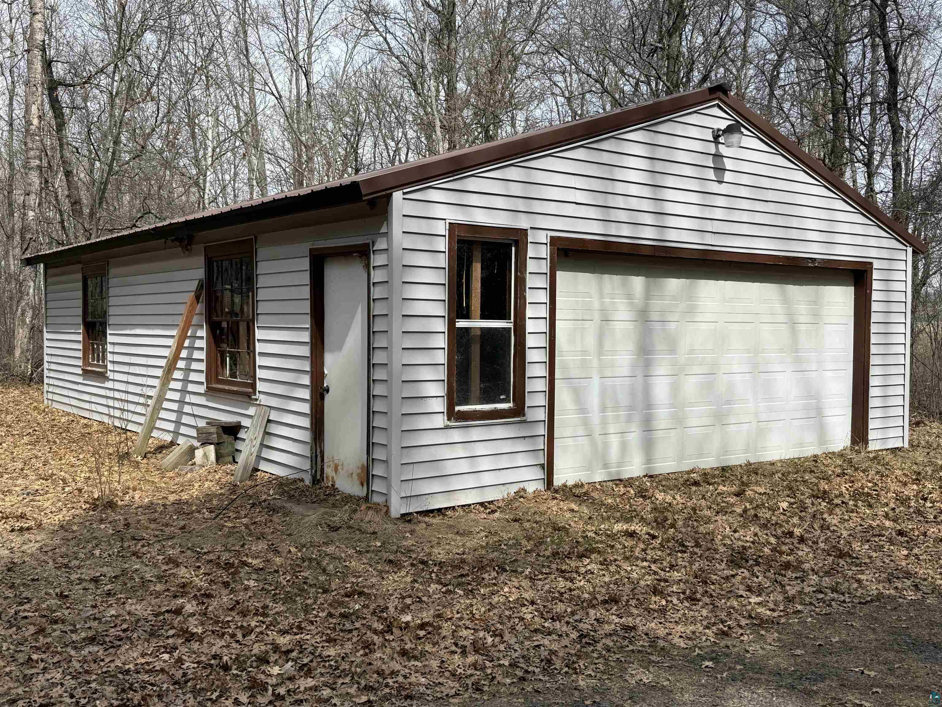 9410 Pine Lake Road Iron River, WI 54847 - Photo 31 of 31 Detached garage structure featuring white siding, a brown trim, a single overhead door, and multiple windows