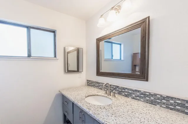 a bathroom with a granite countertop sink a mirror and a
