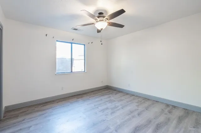 an empty room with wooden floor and ceiling fan