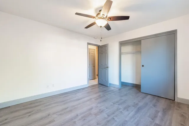an empty room with wooden floor and ceiling fan
