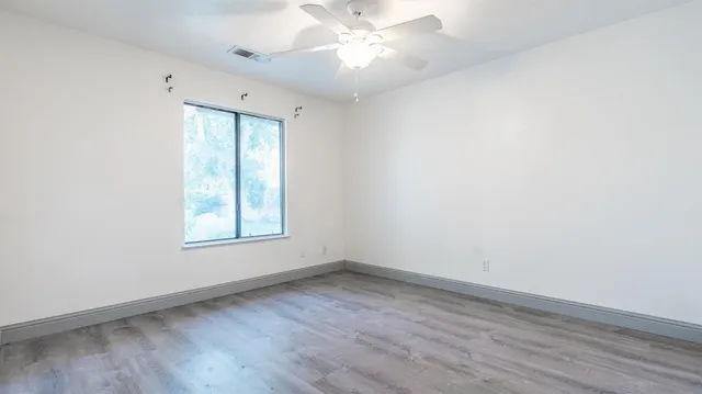 an empty room with wooden floor and windows