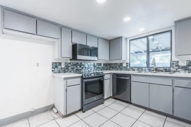 a kitchen with granite countertop white cabinets stainless steel appliances and a sink