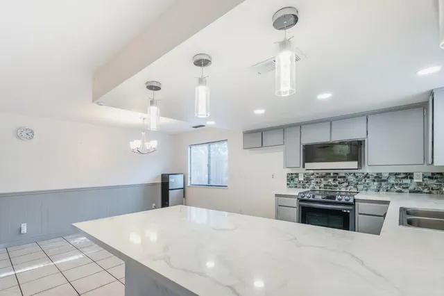 a kitchen with stainless steel appliances kitchen island granite countertop a stove a sink a refrigerator and white cabinets with wooden floor