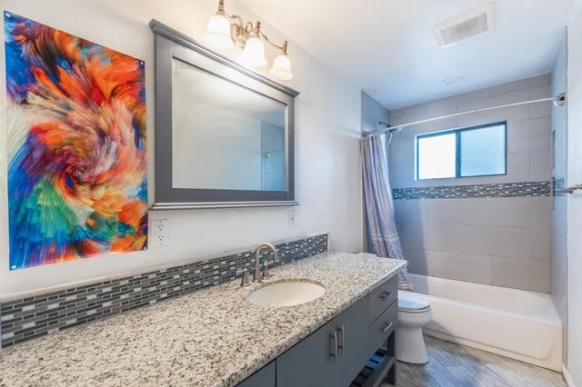 a bathroom with a granite countertop sink a mirror and a bathtub