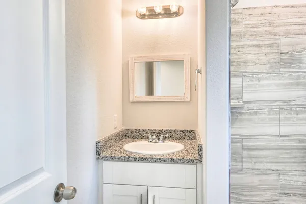 a bathroom with a granite countertop sink and a mirror