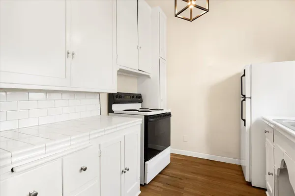 a kitchen with stainless steel appliances granite countertop a refrigerator a sink and white cabinets