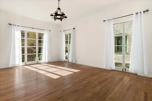 a view of an empty room with wooden floor and windows