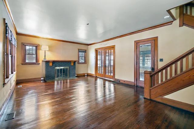 an empty room with wooden floor fireplace and windows