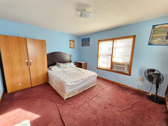 a bedroom with a bed and window with chair