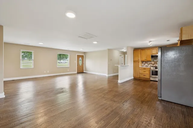 an empty room with wooden floor and windows