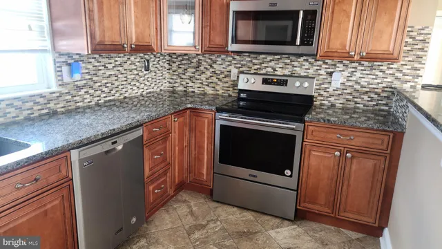 a kitchen with granite countertop a stove top oven microwave and cabinets