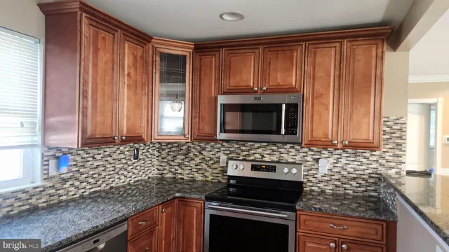 a kitchen with granite countertop a stove sink and microwave