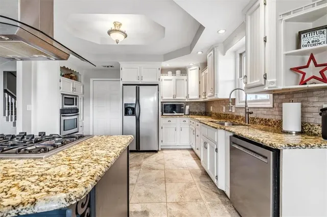 a large kitchen with granite countertop a sink stainless steel appliances and cabinets