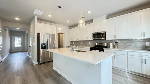 a kitchen with stainless steel appliances a stove top oven a sink a refrigerator and cabinets