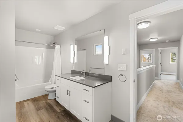 a bathroom with a granite countertop sink a toilet a mirror and shower