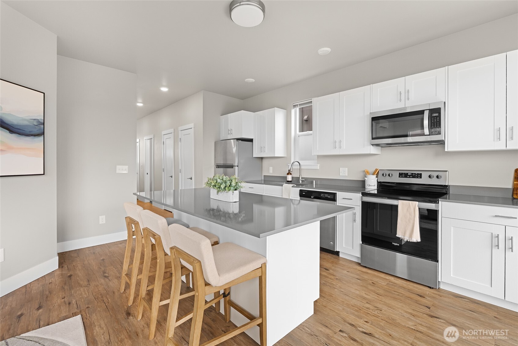 1884 Front Street, Unit A Lynden, WA 98264 - Photo 9 of 35 a kitchen with stainless steel appliances kitchen island granite countertop a stove a sink a refrigerator and white cabinets with wooden floor