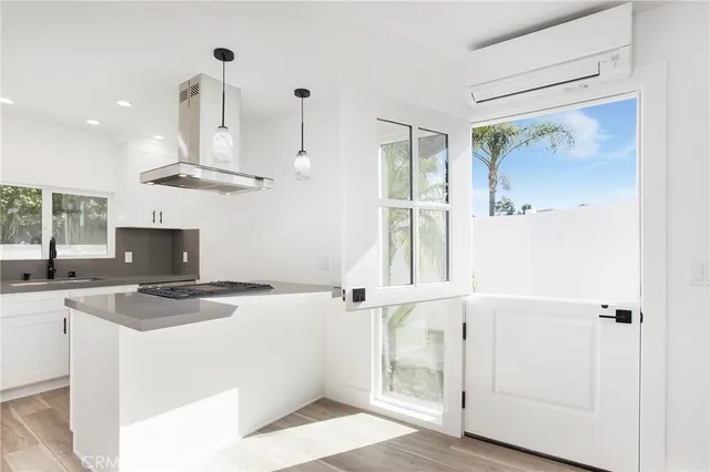 a kitchen with stainless steel appliances a refrigerator a sink dishwasher a stove and a dining table with wooden floor