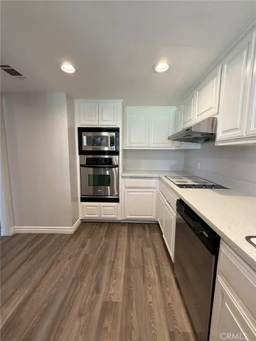 a kitchen with granite countertop a stove cabinets and a wooden floor