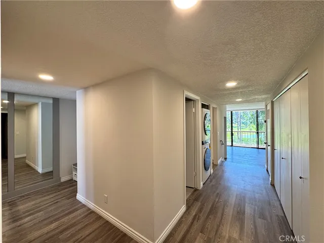 a view of a hallway with wooden floor and closet