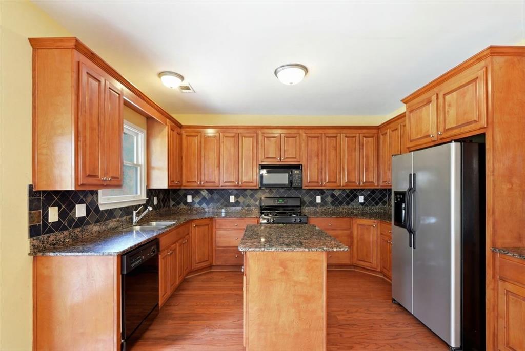 3420 Bulloch Lake Road Loganville, GA 30052 - Photo 24 of 57 a kitchen with stainless steel appliances granite countertop a refrigerator a stove a sink dishwasher and wooden cabinets with wooden floor