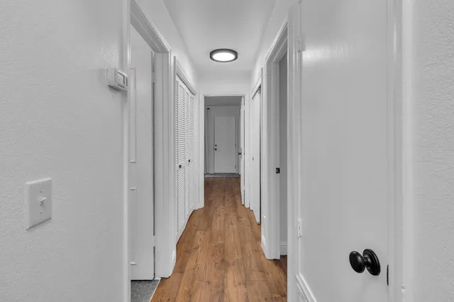 a view of a hallway with wooden floor and a bathroom