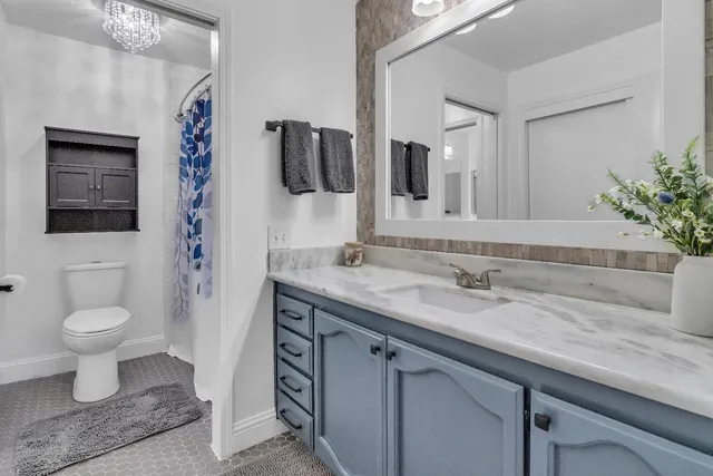 a bathroom with a granite countertop sink a toilet and mirror