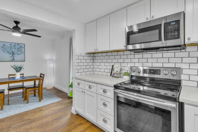 a kitchen with stainless steel appliances a stove a sink cabinets and wooden floor